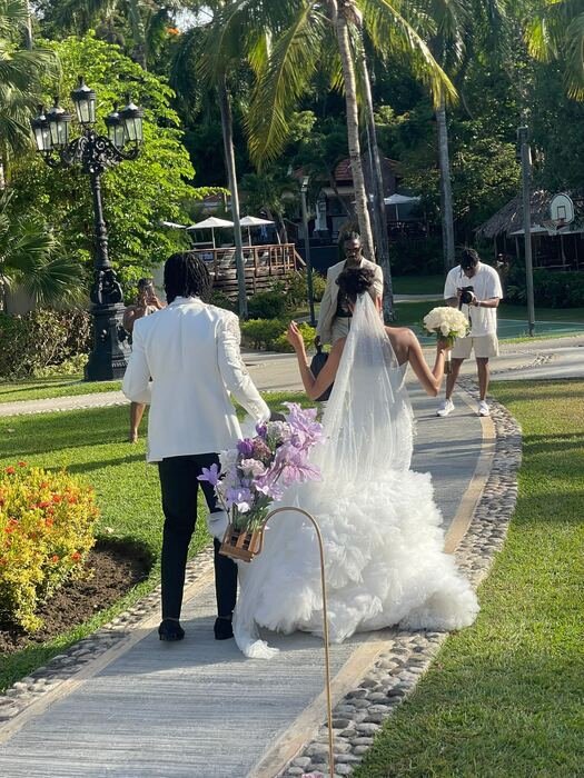 Bride and groom walking down a palm-lined path at their destination wedding