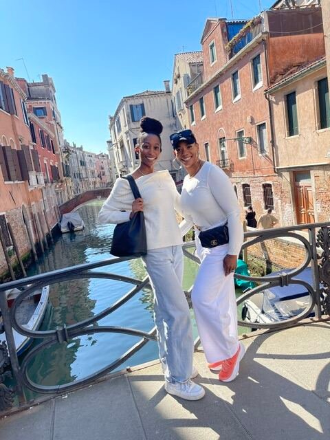 Two travelers posing on a bridge over a Venice canal
